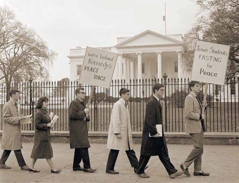 Jack Chapman, one of 14 Grinnell students  going to Washington, D.C., to demonstrate against
the resumption of nuclear testing in the atmosphere by the United States, prepares for the long
journey Eastward. Looking on are Celia Chorosh, Mary Lou Beaman and Mary Mitchell. Page 38 1962 cyclone